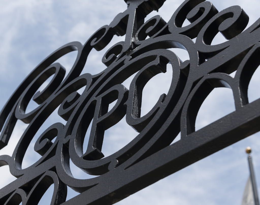Detail of the Phelan Gates at River Avenue, highlighting the letters PC
