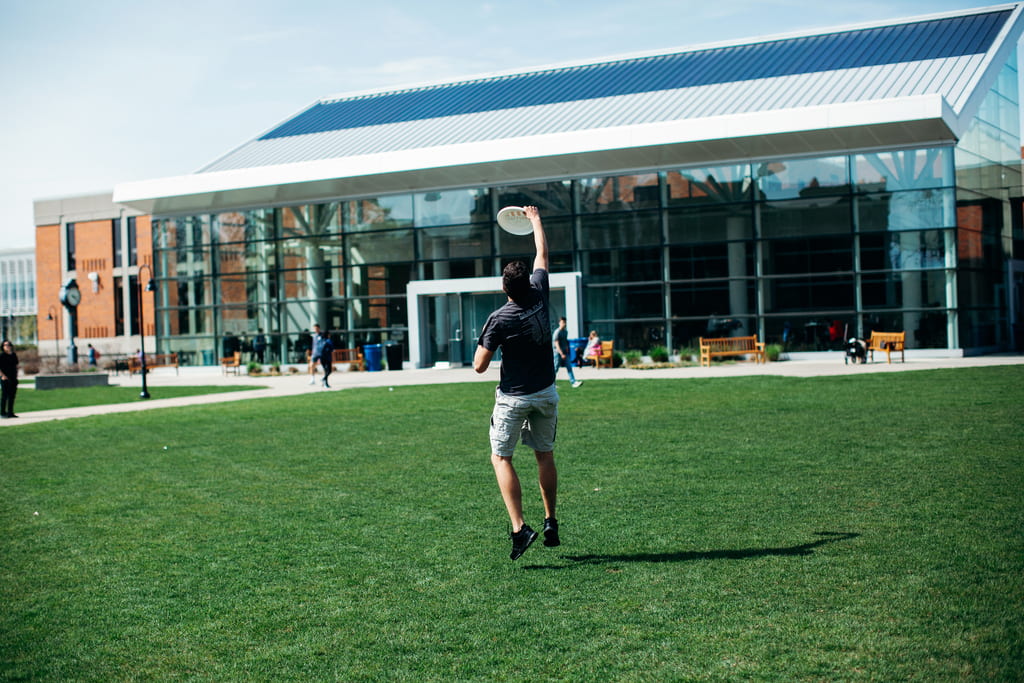 Student catches a frisbee outside the Slavin Center.