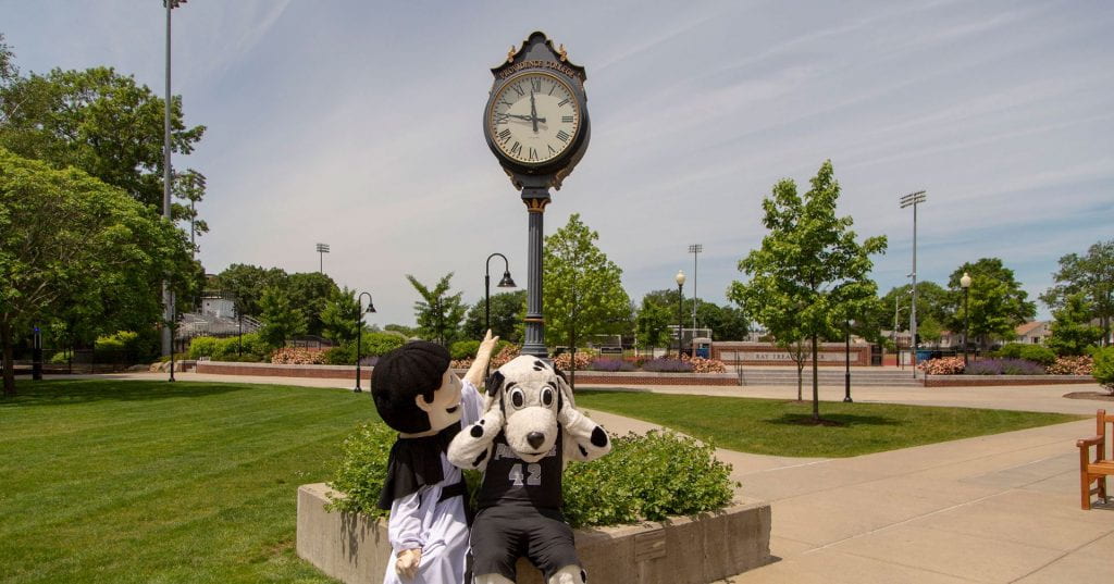 Friar Dom points to the clock in front of Slavin while Huxley holds his head, worried they are late.